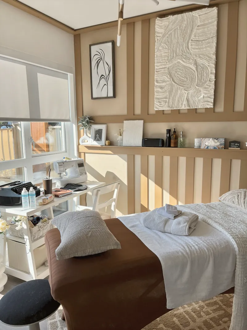 A calm, finished treatment studio with a massage table and warm neutral décor